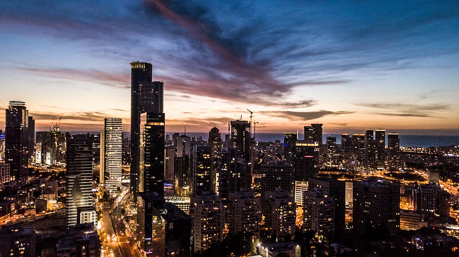 The Tel Aviv skyline at dusk with the Azrieli towers glowing against a pink and indigo sky
